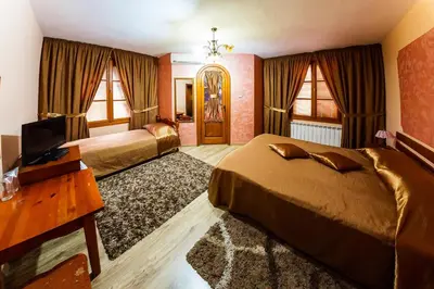 a hotel room with two beds and a television at Family Hotel Ogi in Asenovgrad