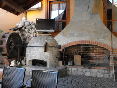 a stone oven with two chairs and a tv at Family Hotel Ogi in Asenovgrad