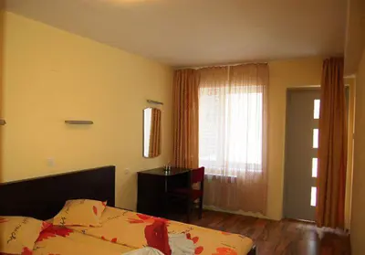 a bedroom with a bed and a desk and a window at Pop Bogomil family hotel in Sofia