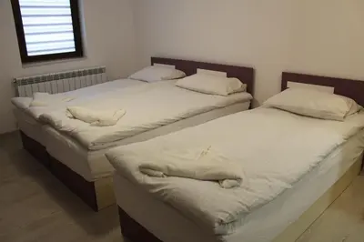 three beds in a room with white sheets and pillows at Къща за гости Мишурови in Smolyan