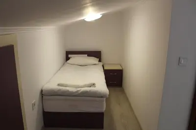 a small room with a bed and a night stand at Къща за гости Мишурови in Smolyan