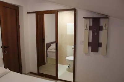 a bathroom with a toilet and a glass shower door at Къща за гости Мишурови in Smolyan
