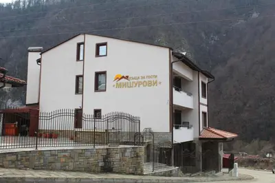 a white building with a sign on the side of it at Къща за гости Мишурови in Smolyan