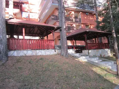 a building with a red fence and some trees at Хотел Магнолия, Hotel Magnoliya in Panichishte