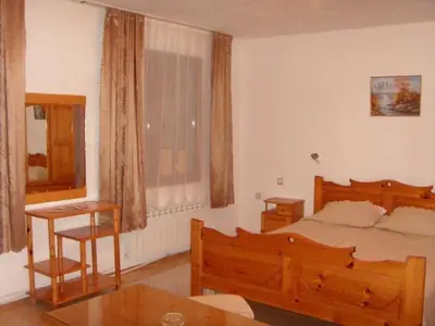 a bedroom with a wooden bed and a table at Family Hotel Markony in Pamporovo