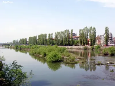a river with trees and buildings in the background at RIVERSIDE APARTMENTS PLOVDIV with free parking in Plovdiv