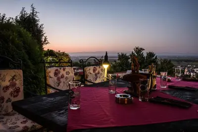 a table with a pink table cloth and a bottle of wine at Chiflika Family Hotel in Asenovgrad