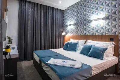 a bedroom with a large bed with blue pillows at 103 Degrees Hotel & Spa in Sapareva Banya