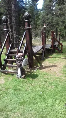 a wooden structure sitting in the grass next to a tree at TES Rila Park Apartments in Borovets