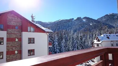 a view from the balcony of a building with snow covered trees at TES Rila Park Apartments in Borovets