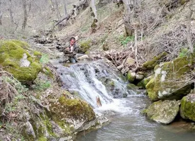 a man sitting on a waterfall next to a creek at Villa Cherven in Teteven