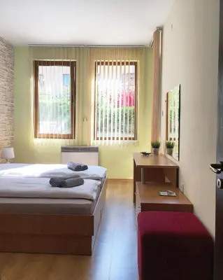 a bedroom with a bed and a table and windows at Snow Apartment - Bansko in Bansko
