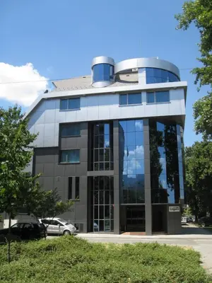 a large glass building with a car parked in front at Hotel Elegance in Asenovgrad