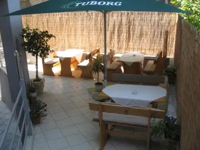 a patio with an umbrella and tables and chairs at Hotel Elegance in Asenovgrad