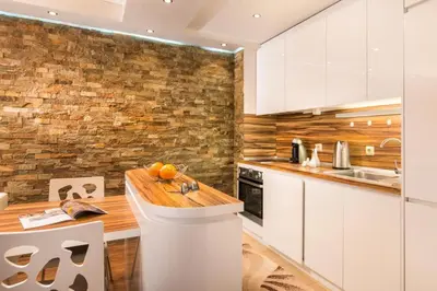 a kitchen with white cabinets and a stone wall at Nice and cozy flat in the center in Sofia