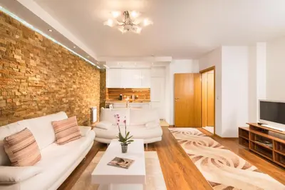 a living room with white furniture and a brick wall at Nice and cozy flat in the center in Sofia