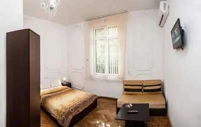 a bedroom with a bed and a chair and a window at Central GuestHouse Five Corners in Sofia
