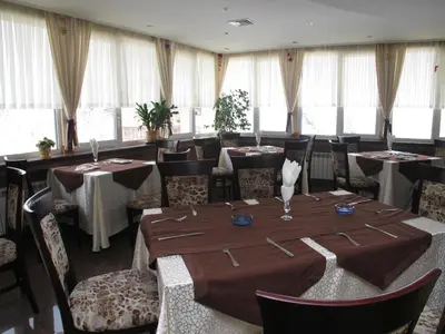 a dining room with tables and chairs and windows at Family Hotel Yagoda88 in Sofia