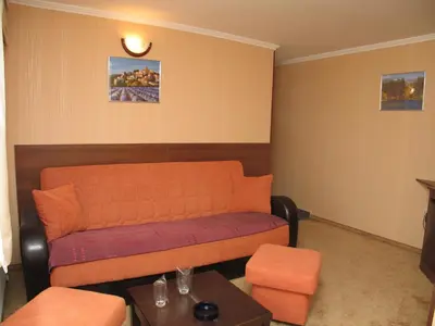 a living room with an orange couch and a table at Family Hotel Yagoda88 in Sofia