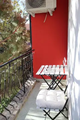 a table and chairs on a balcony with a red wall at Hotel Color in Asenovgrad