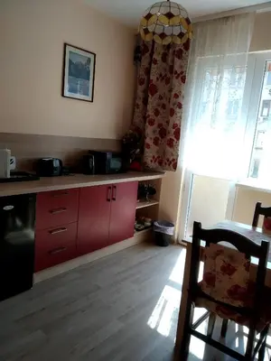 a kitchen with red cabinets and a table and a window at Maria Louisa Apartment in Sofia