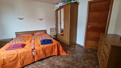 a bedroom with a bed with orange sheets and a dresser at Apartment 9 in Pamporovo