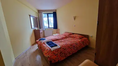 a bedroom with a bed with a red comforter and a window at Apartment 9 in Pamporovo