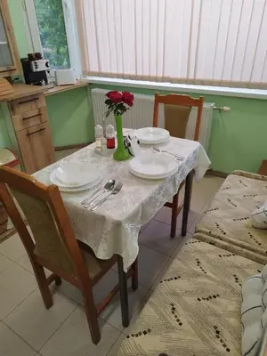 a table with plates and a vase with flowers on it at Aleks Guest House in Samokov