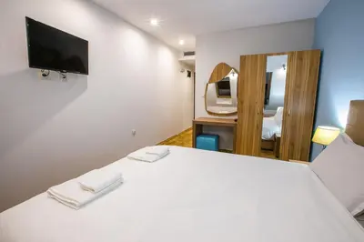 a bedroom with a white bed and a tv at Hotel Andon Angelov in Sandanski