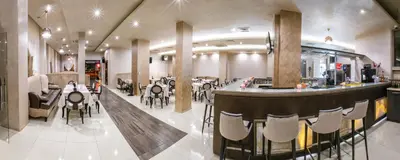 a restaurant with a bar and some tables and chairs at Hotel Andon Angelov in Sandanski
