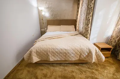 a bedroom with a bed with a white comforter at Hotel Andon Angelov in Sandanski
