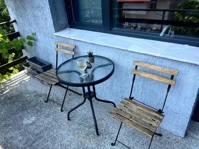 a glass table and two chairs sitting next to a window at Bankya Guest House - Sofia in Bankya