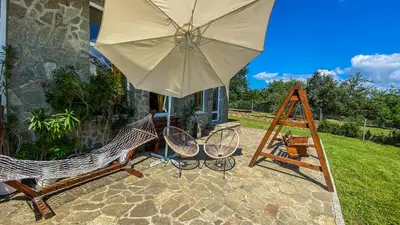 a patio with two chairs and an umbrella at Guest House Au Nature in Golyama Zhelyazna