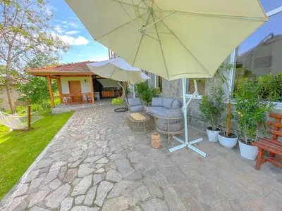 a patio with an umbrella and a chair and a bench at Guest House Au Nature in Golyama Zhelyazna