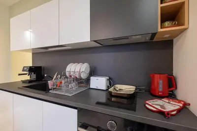 a kitchen with white cabinets and a black counter top at Vitosha Blvd Luxury 2-Bedroom, 2-Bathroom with Balcony in Sofia