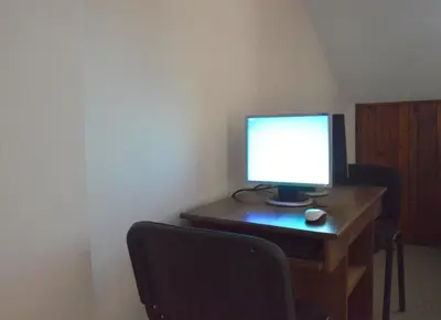 a computer monitor on a wooden desk with a chair at Hotel Dumanov in Bansko
