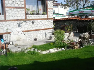 a garden with a teddy bear in front of a building at Hotel Dumanov in Bansko