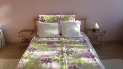 a bed with a floral comforter and three pillows at Cosy place close to the Center in Sofia