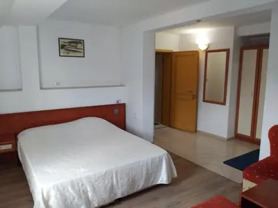 a bedroom with a white bed and a red chair at ХОТЕЛ НИК in Asenovgrad