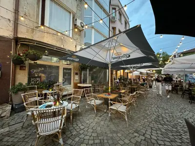 an outdoor cafe with tables and chairs and an umbrella at Mini Hotel-Bohemi in Plovdiv