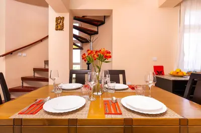 a dining room table with white plates and red flowers at Roof top terrace maisonette in Plovdiv