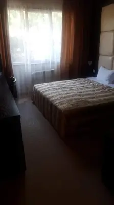 a bedroom with a bed and a window with curtains at Hotel Villa Ofir in Sandanski