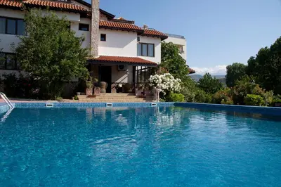 a swimming pool in front of a house at Hotel Villa Ofir in Sandanski