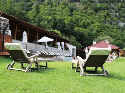 two chairs and a table in the grass in front of a house at Хотел Аква Варвара in Varvara