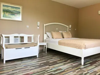 a bedroom with two white beds and a wooden floor at Yaev Family Hotel in Karlovo
