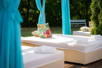 a row of white beds with blue curtains at Ostrova Holiday Village in Beli Osŭm