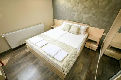 a bedroom with a bed with white sheets and pillows at Апартамент Радост Сандански in Sandanski