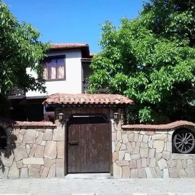 a house with a stone wall and a wooden door at Семеен хотел НАЦИОНАЛ in Mineralni Bani
