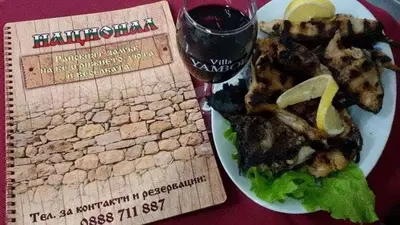 a plate of food on a table with a glass of wine at Семеен хотел НАЦИОНАЛ in Mineralni Bani