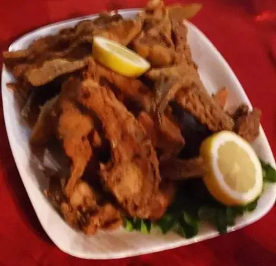 a plate of fried food with a lemon on it at Семеен хотел НАЦИОНАЛ in Mineralni Bani